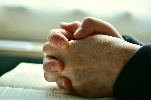 Photo of praying hands atop a Bible in an article about devotion to God on the SCCOC truthseekers website for the Church of Christ in Santa Clara.