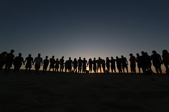 Photo of a group of people in silhouette against a backdrop of a horizon.