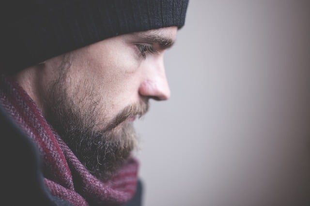 Photo of a bearded man looking down.