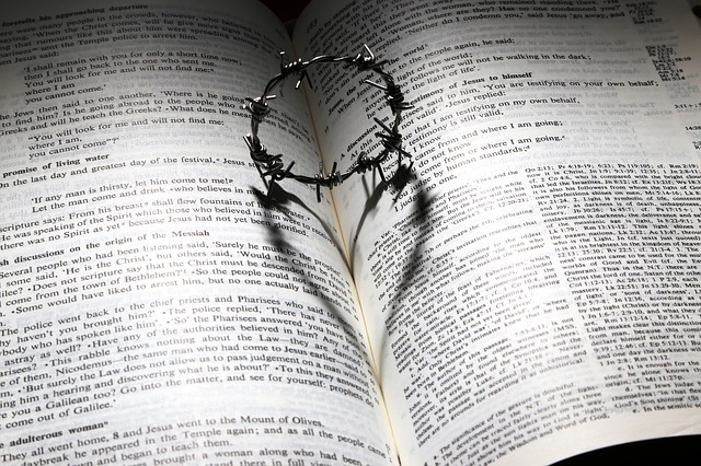 Photo of a Bible with open pages, holding a ring resembling the crown of thorns worn by Jesus, making the outline of a heart.